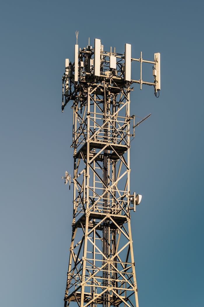 Close-up of a telecom tower with antennas and clear blue sky background.